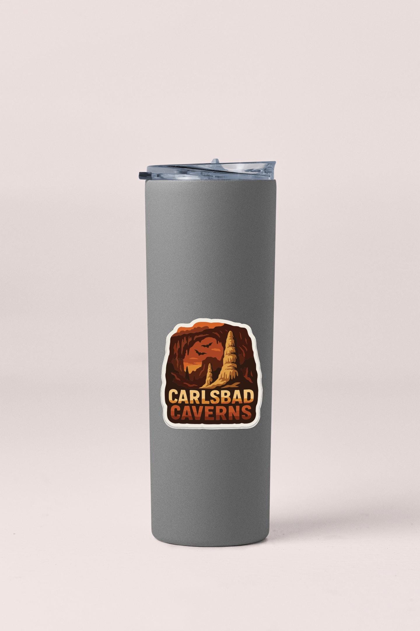 A gray insulated tumbler with a sticker that says "Carlsbad Caves".