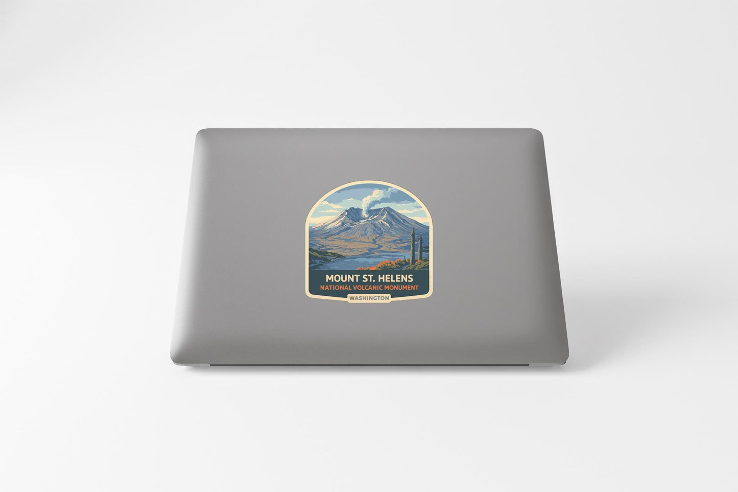 a sticker on the back of a laptop, depicting a mountain landscape with a lake and a mountain range.