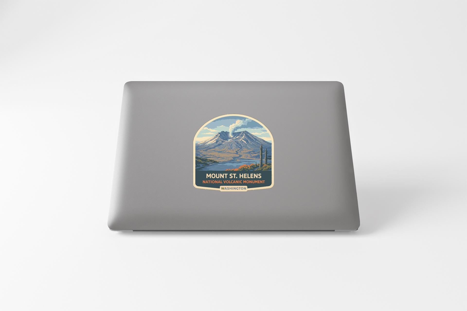 a sticker on the back of a laptop, depicting a mountain landscape with a lake and a mountain range.