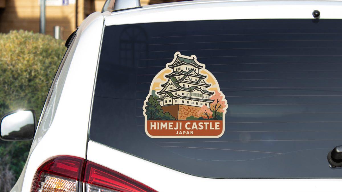 A sticker on the rear window of a car that features an illustration of the Himeji Castle in Japan.