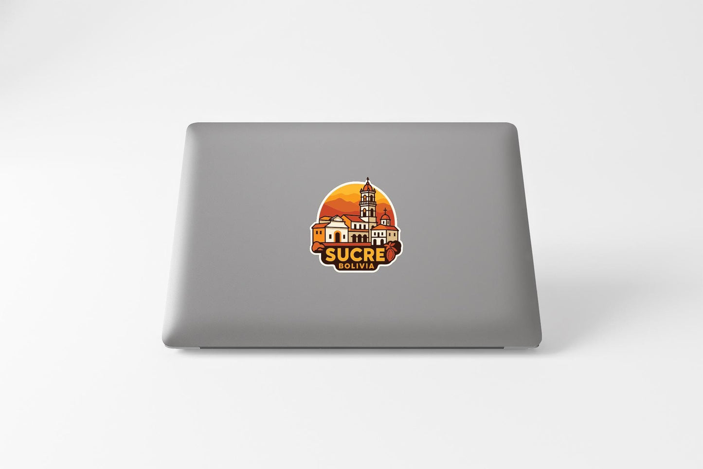 a sticker with a graphic of a building and the text "SUCRE BOLIVIA" on the back of a laptop.