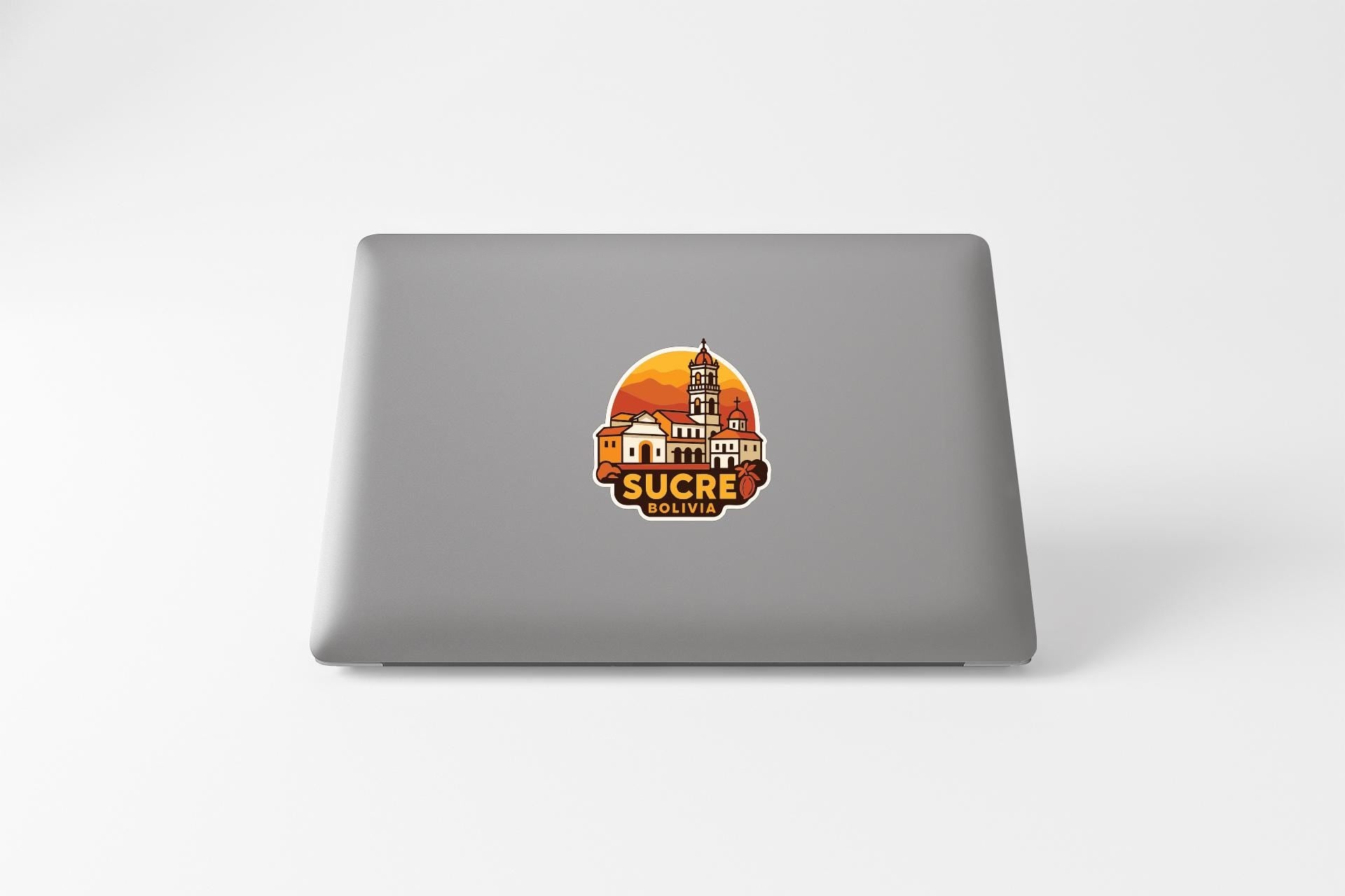 a sticker with a graphic of a building and the text "SUCRE BOLIVIA" on the back of a laptop.