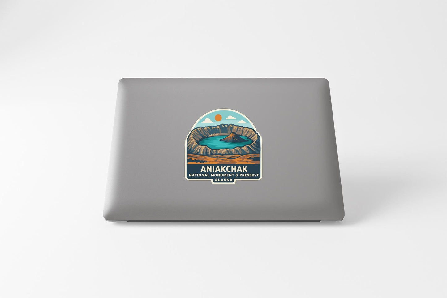 a sticker or decal on the back of a laptop, depicting a scenic landscape with mountains, a lake, and a sunset.