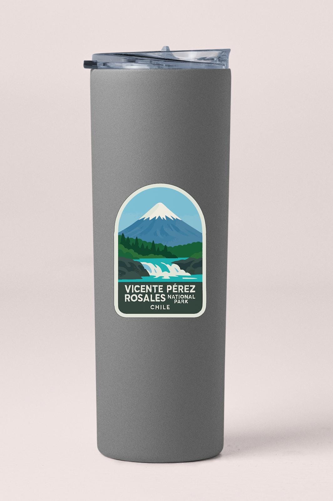 A gray tumbler with a label that features a mountain landscape and text.