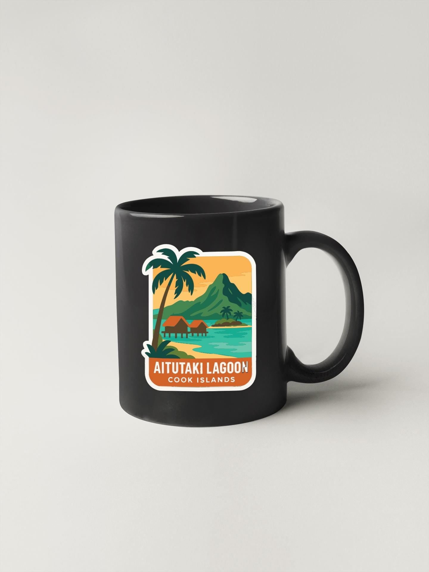 A black coffee mug with a tropical island design featuring a palm tree, mountains, and a beach.