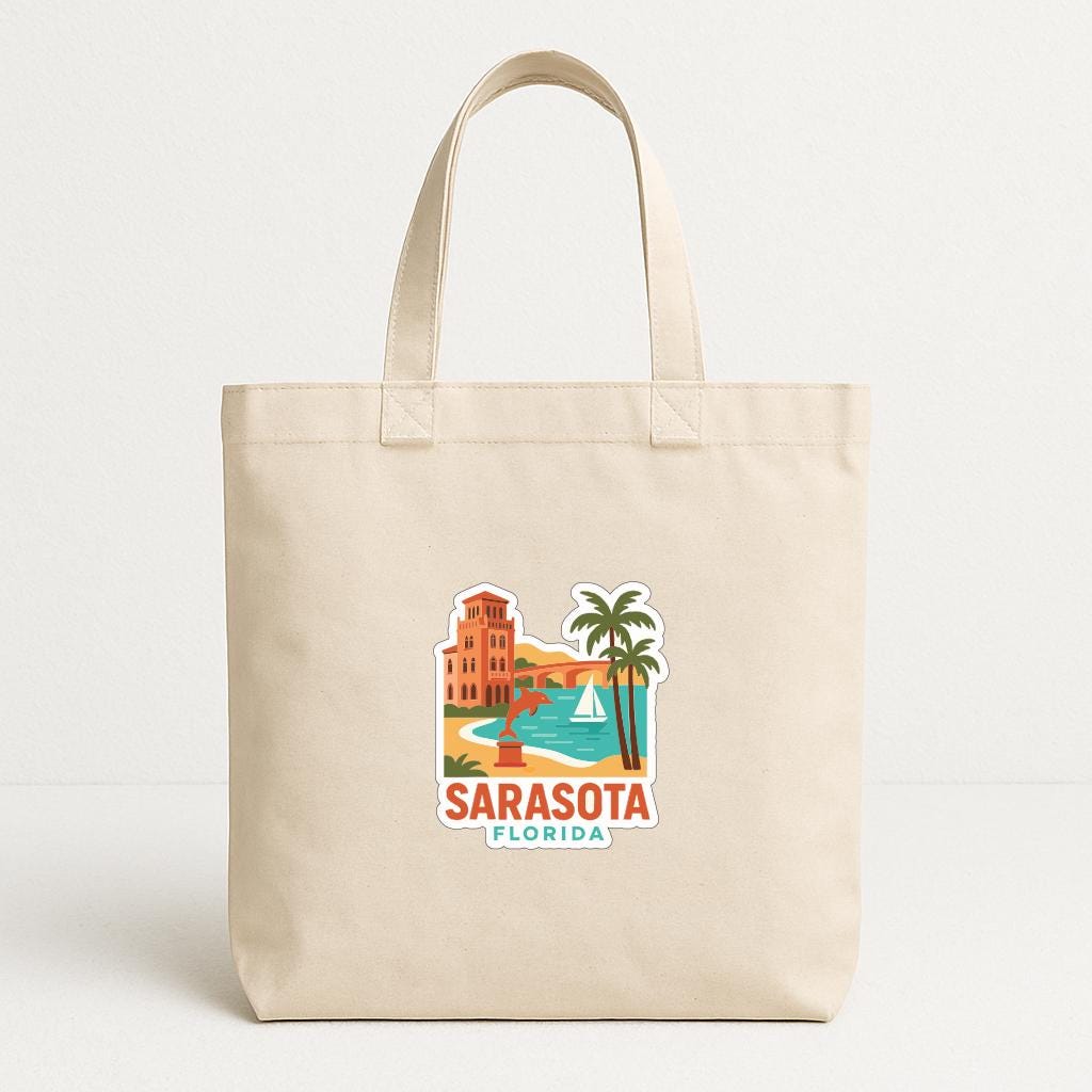 A beige tote bag with a printed design depicting a beach scene and palm trees, along with the text "SARASOTA, FLORIDA".