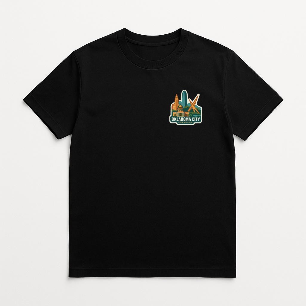 A black t-shirt with a graphic design on the front, depicting a city skyline with a prominent skyscraper.