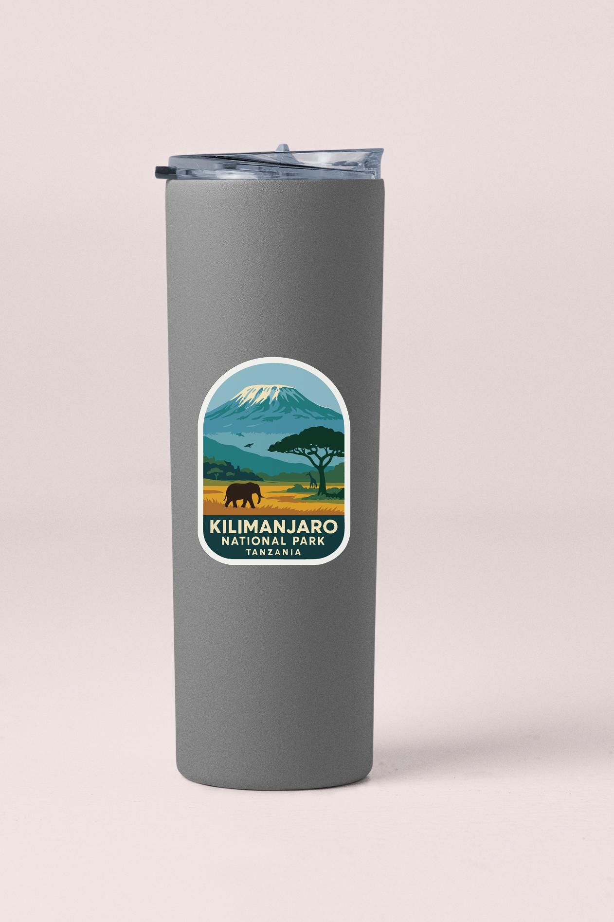 A gray tumbler with a sticker depicting a mountain landscape and an elephant.
