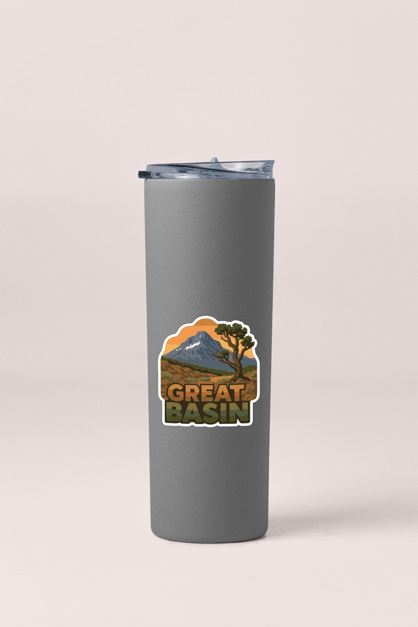 A gray insulated tumbler with a sticker depicting a mountain and the text "GREAT BASIN" printed on it.