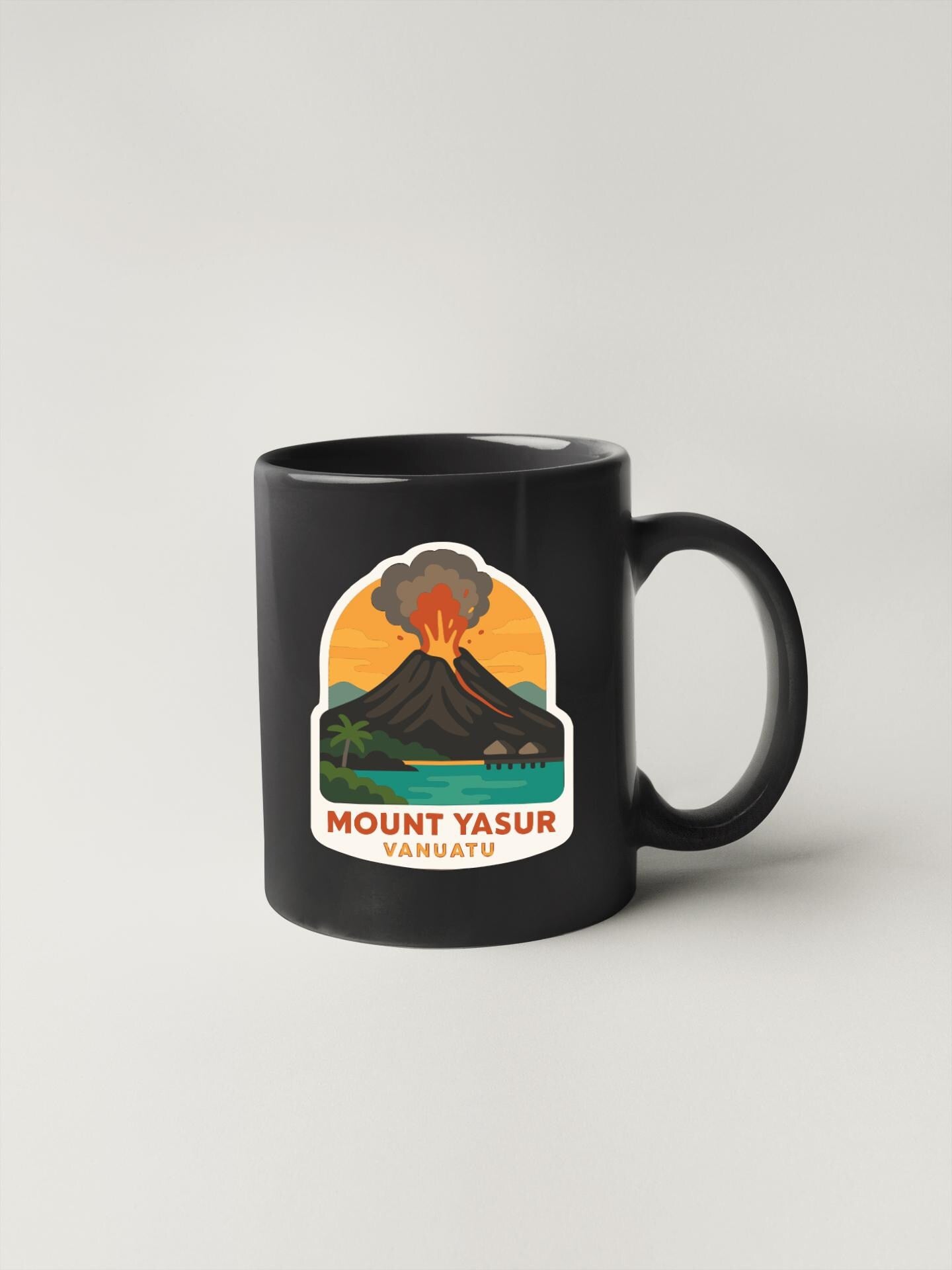 A black coffee mug with a graphic design depicting a volcano and a tropical landscape.