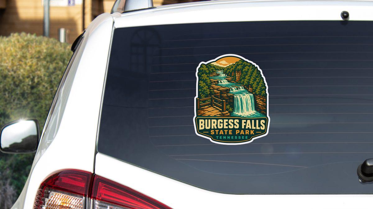 A sticker on the rear window of a white vehicle, depicting a scenic landscape with a waterfall and forest.