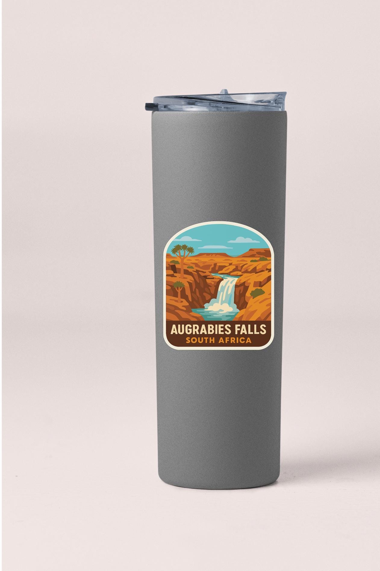 A gray tumbler with a label that features an illustration of Augrabies Falls, a famous waterfall located in South Africa.