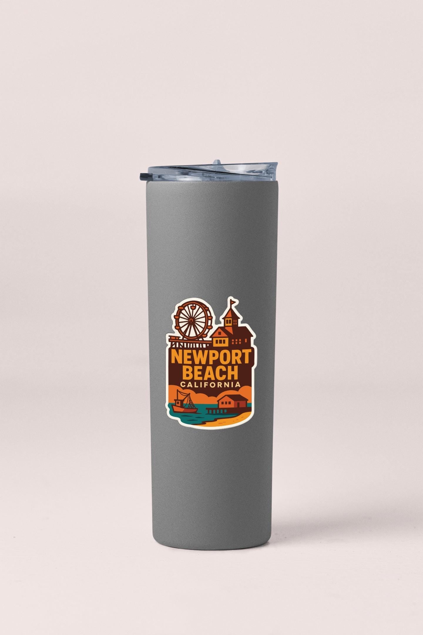A gray insulated tumbler with a label that says "NEWPORT BEACH CALIFORNIA" and features an illustration of a beach and amusement park.
