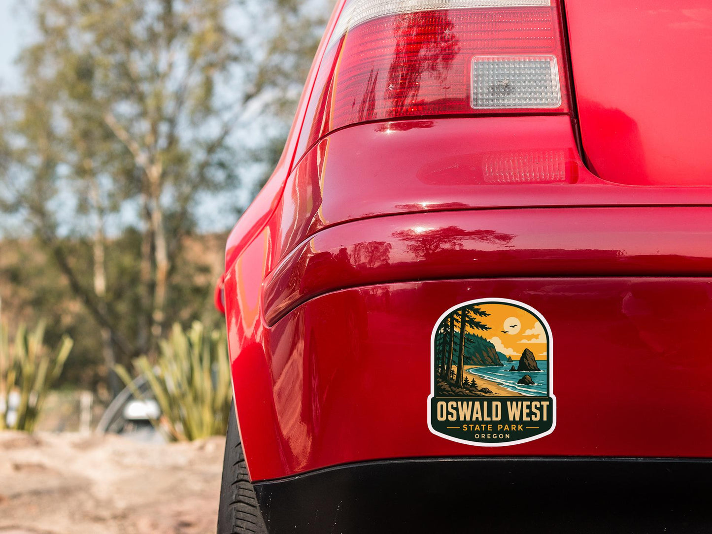 the rear end of a red car with a sticker on the back window that reads "OSWALD WEST STATE PARK OREGON".