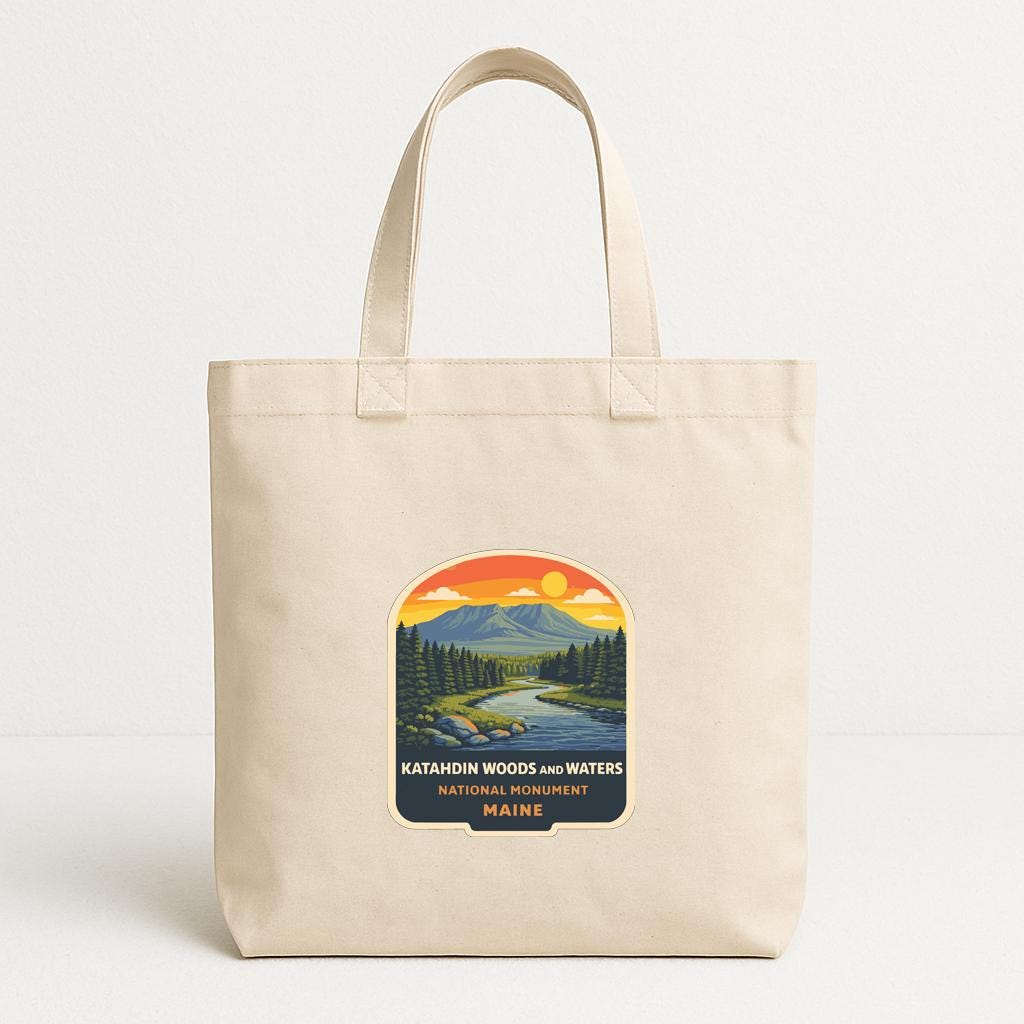 A beige tote bag with a printed design depicting a scenic landscape with mountains, trees, and a river.