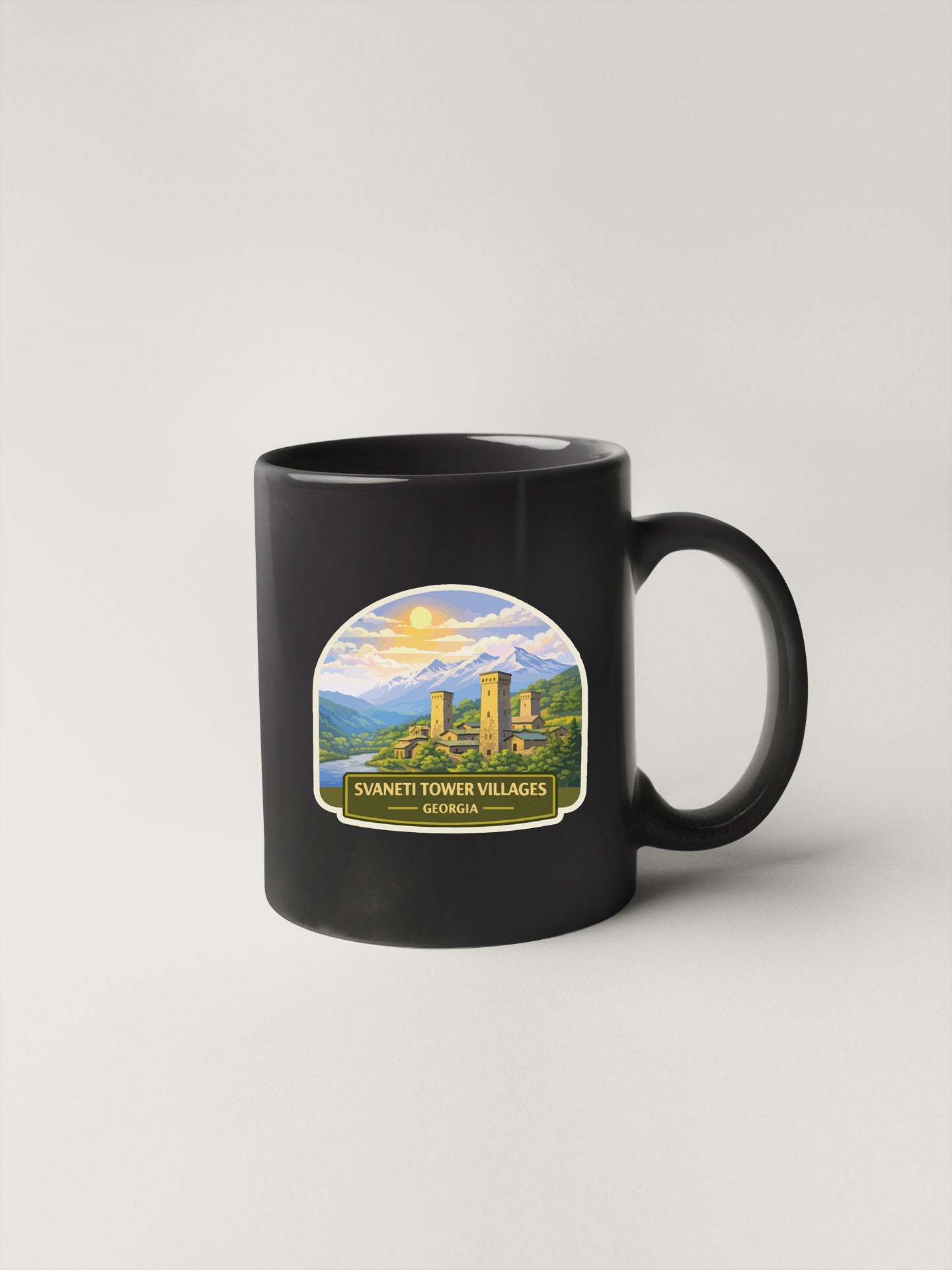A black coffee mug with a label depicting the Svaneti Tower Villages in Georgia.