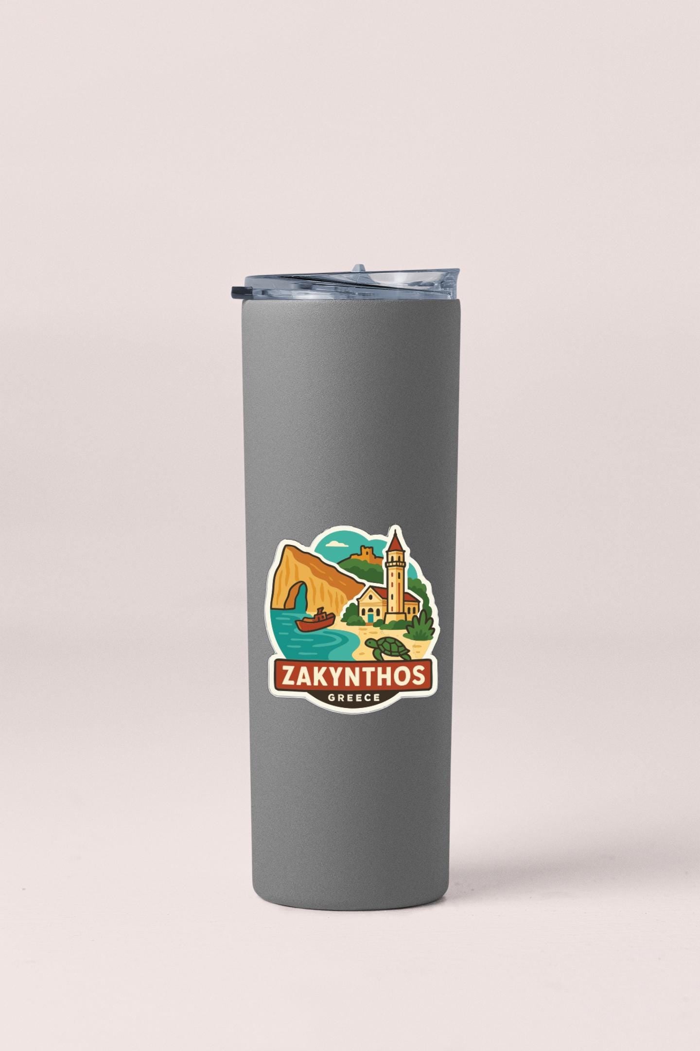 A gray insulated tumbler with a sticker depicting a scenic landscape and the text "ZAKYTHOS Greece".