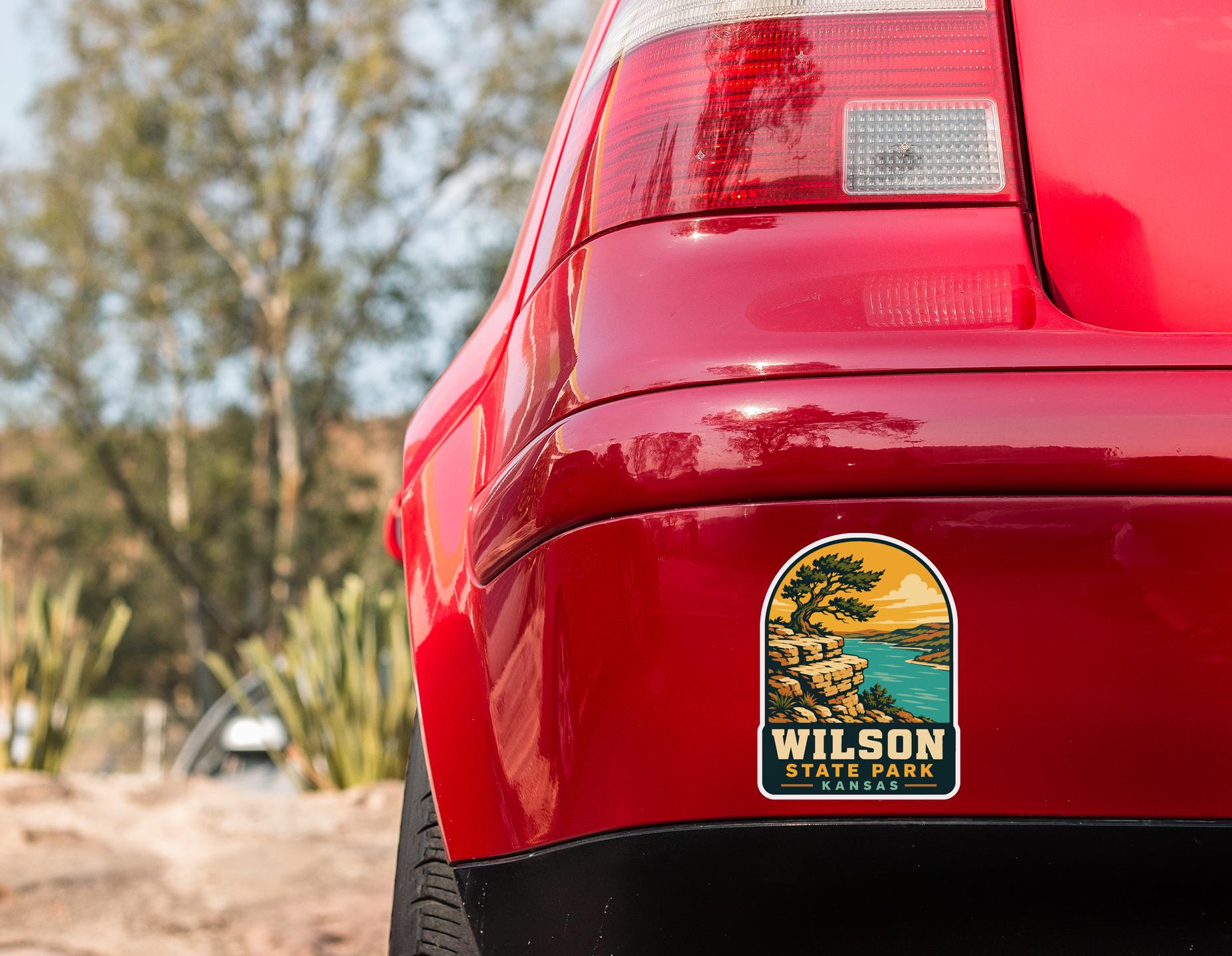 the rear end of a red car with a sticker on the trunk that says "Wilson State Park Kansas".