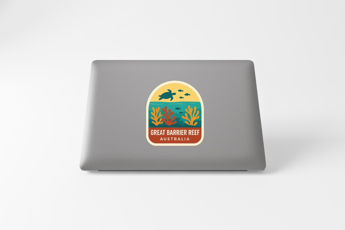a sticker or decal on the back of a laptop, depicting a tropical scene with a turtle, coral, and other marine life.