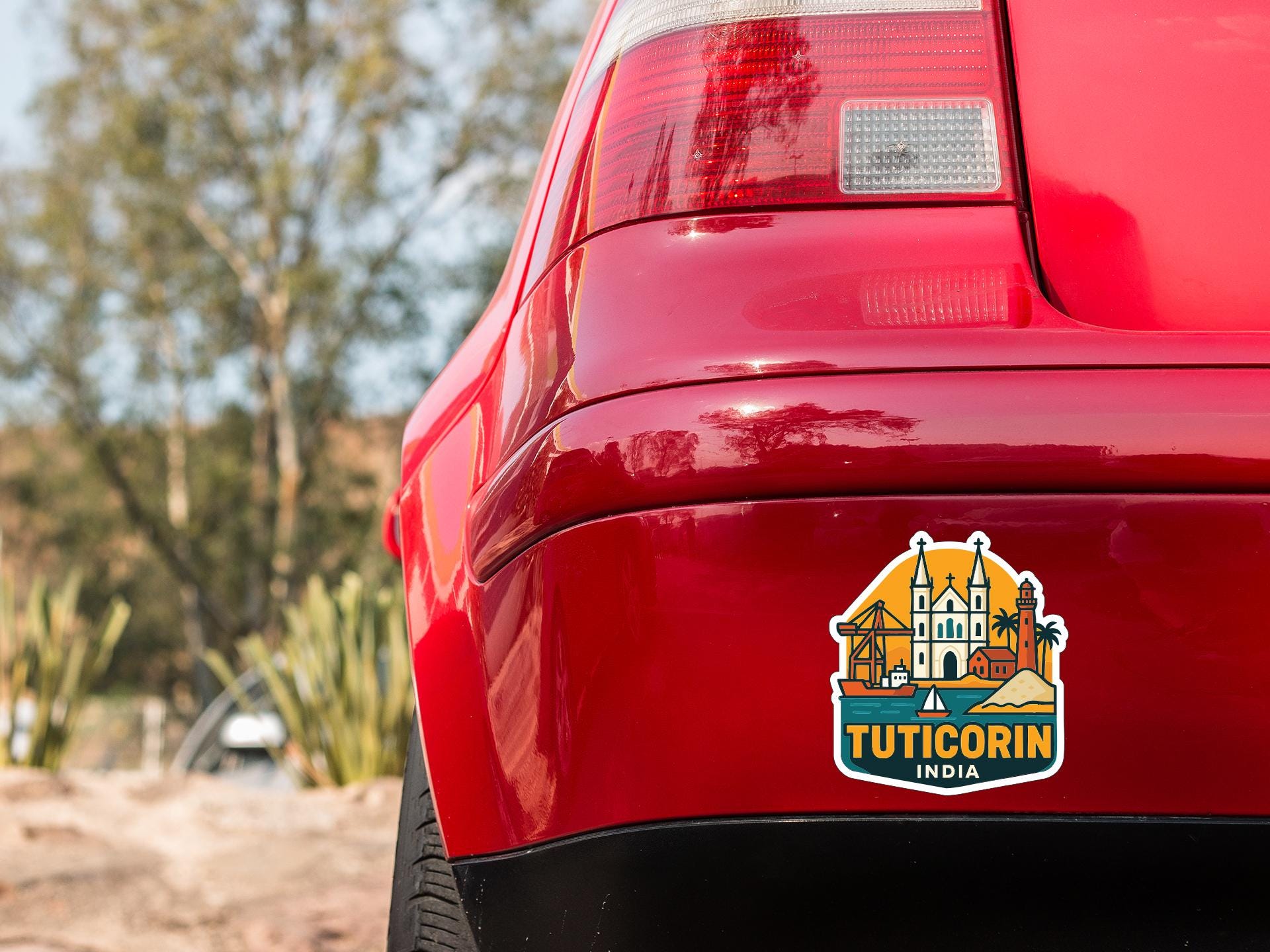 the rear end of a red car with a sticker on the trunk that says "TUTICORIN INDIA".