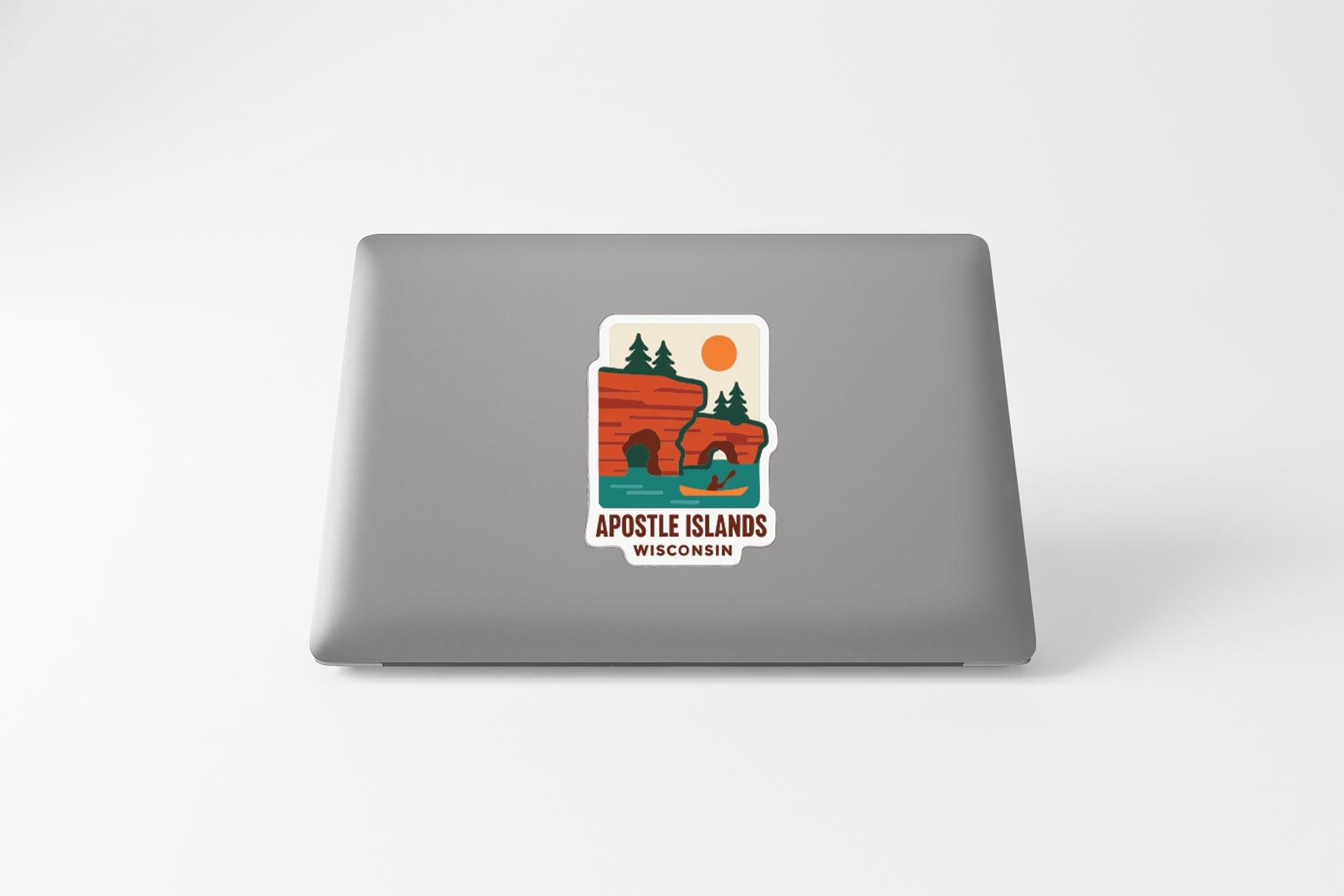 a sticker on the back of a laptop that displays a scenic landscape with a lake, mountains, and a canoe.