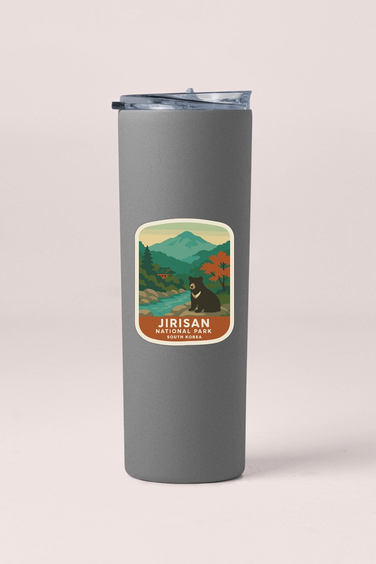 A gray insulated tumbler with a label featuring a bear and mountains in the background.