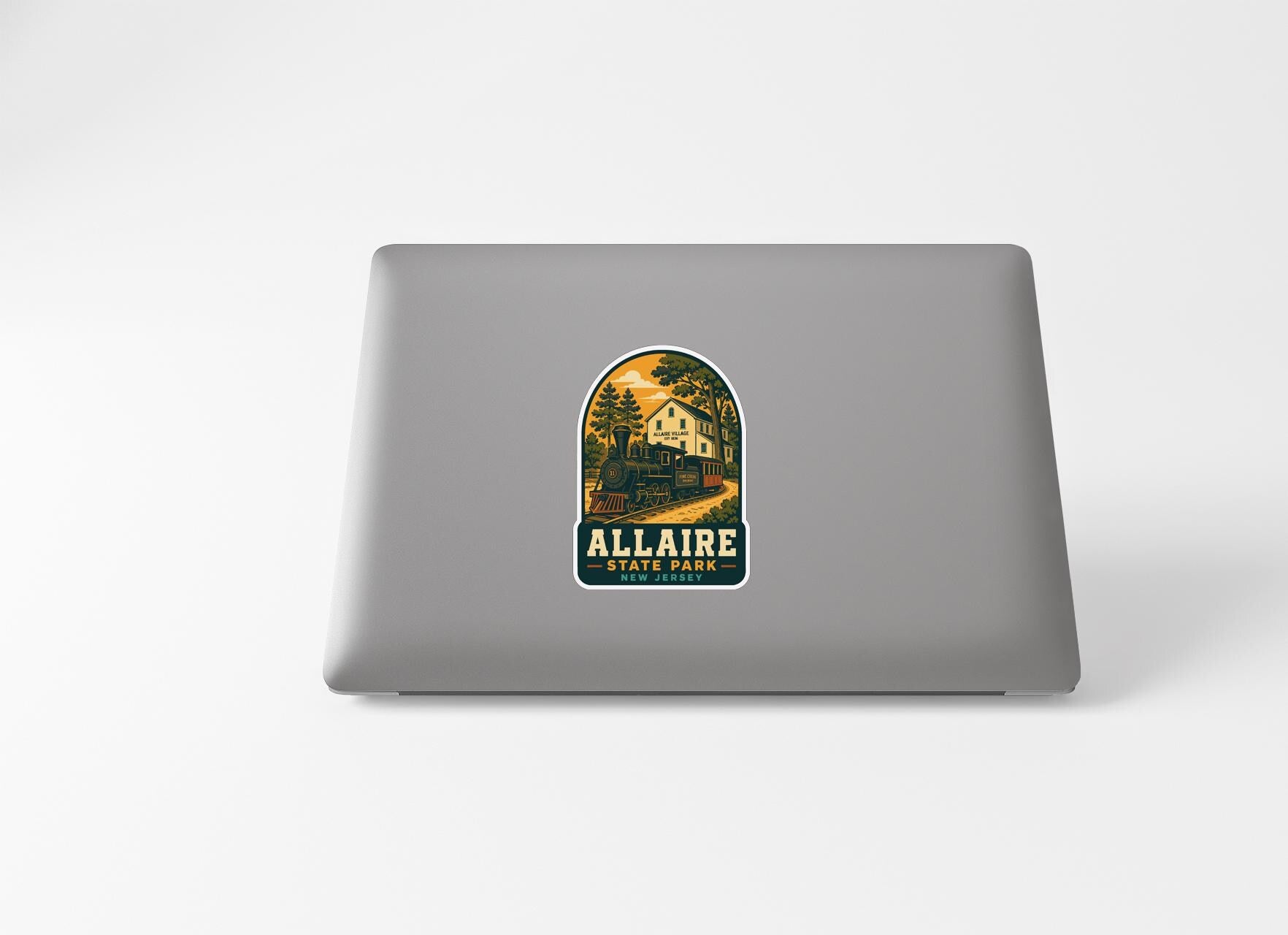 a sticker with a scenic illustration of a train and a house, along with the text "ALLAIRE STATE PARK" printed on it.