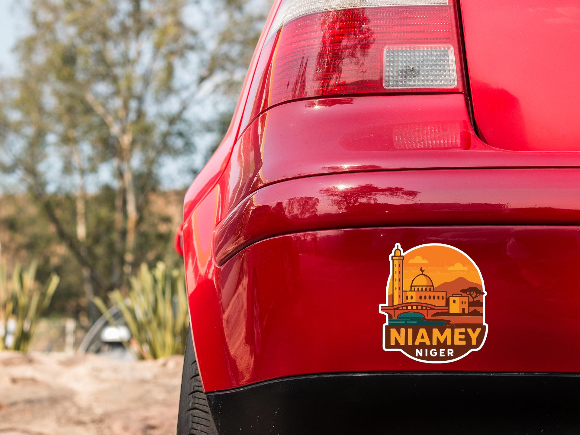 the rear end of a red car with a sticker on the trunk that says "NIAEMY NIGER".