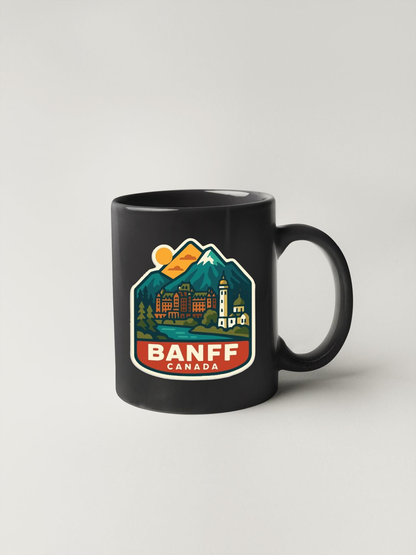 A black coffee mug with a colorful graphic design depicting a mountain landscape and the text "BANFF CANADA" printed on it.
