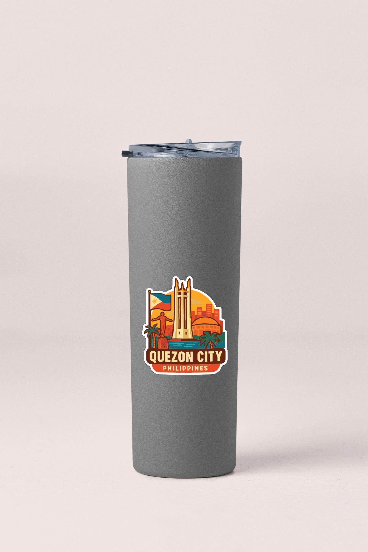 A gray insulated tumbler with a sticker depicting the Quzon City, a landmark in the Philippines.