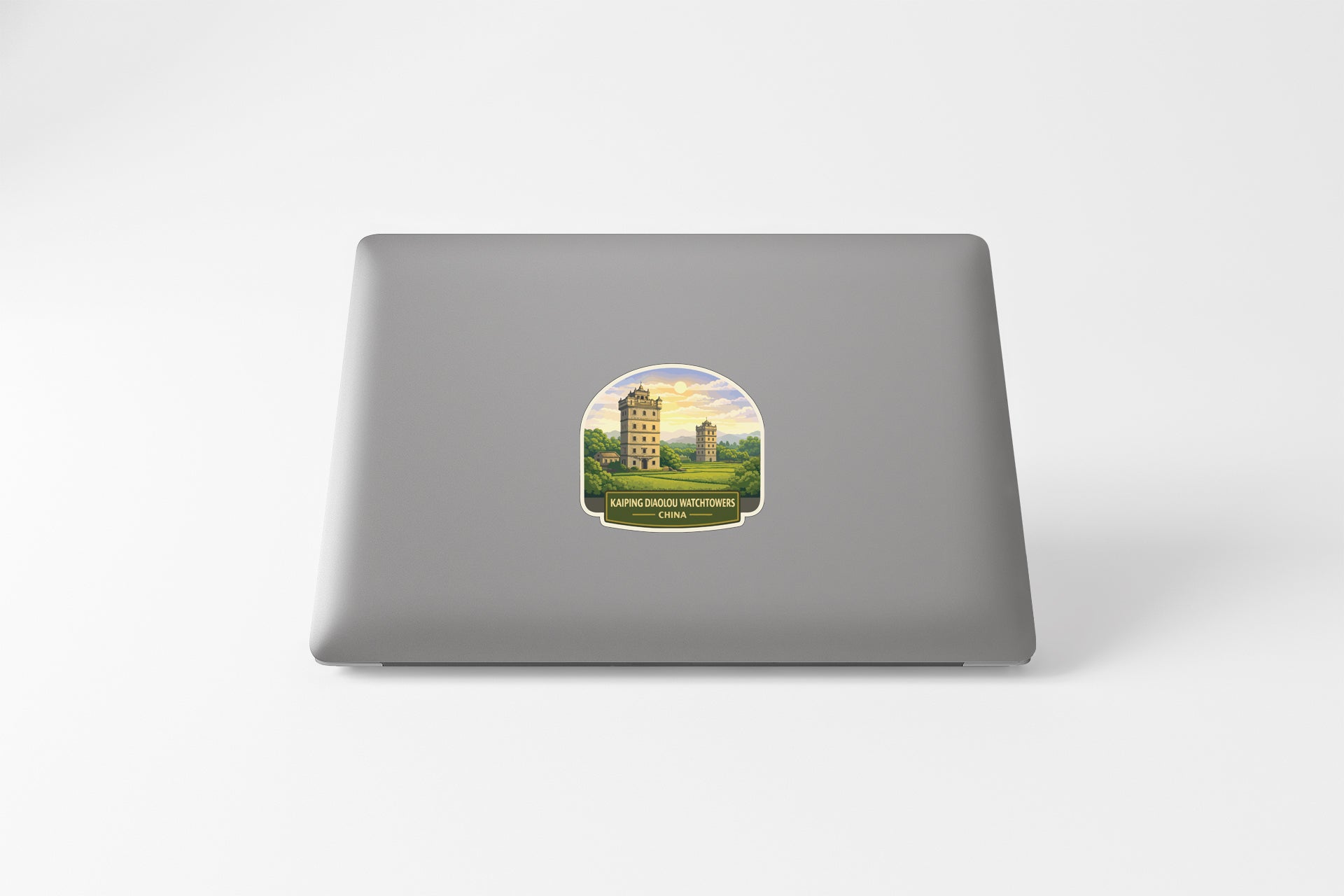 a sticker on the back of a laptop, depicting a building with a tower and a landscape.