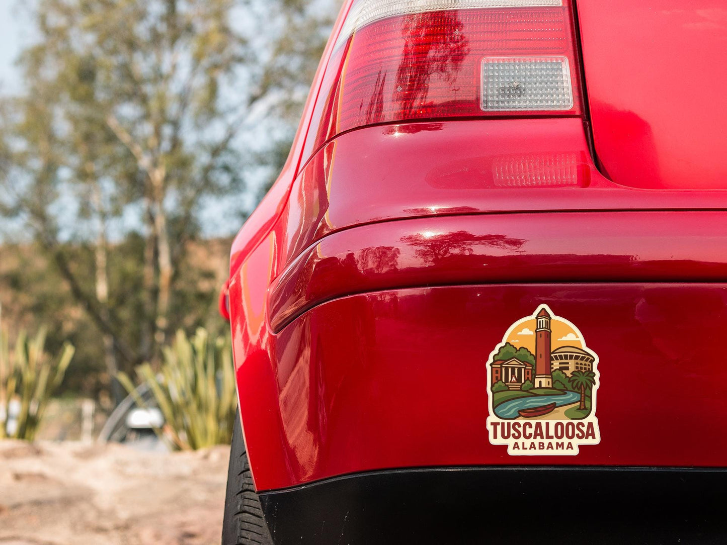 the rear end of a red car with a sticker on the trunk that says "Tuscaloosa Alabama".