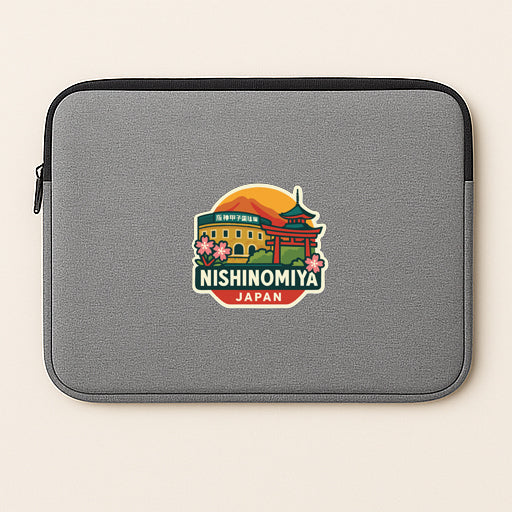A gray laptop sleeve with a sticker depicting the Nishinomiya Temple in Japan.