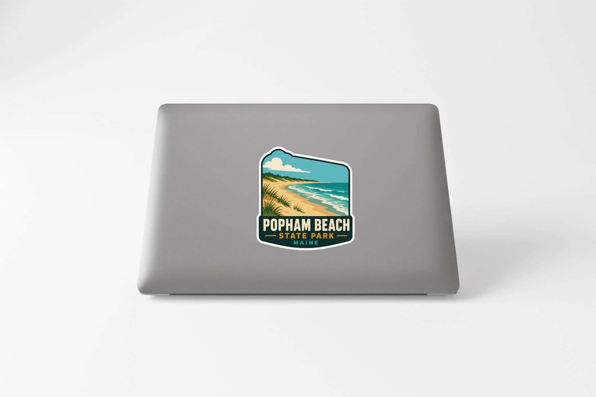 A sticker on the back of a laptop, depicting a beach scene with a palm tree and ocean.