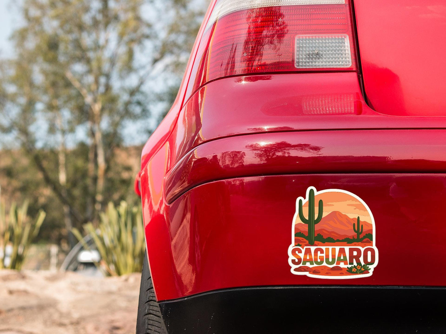 the rear end of a red car with a sticker on the trunk that says "Saguaro".