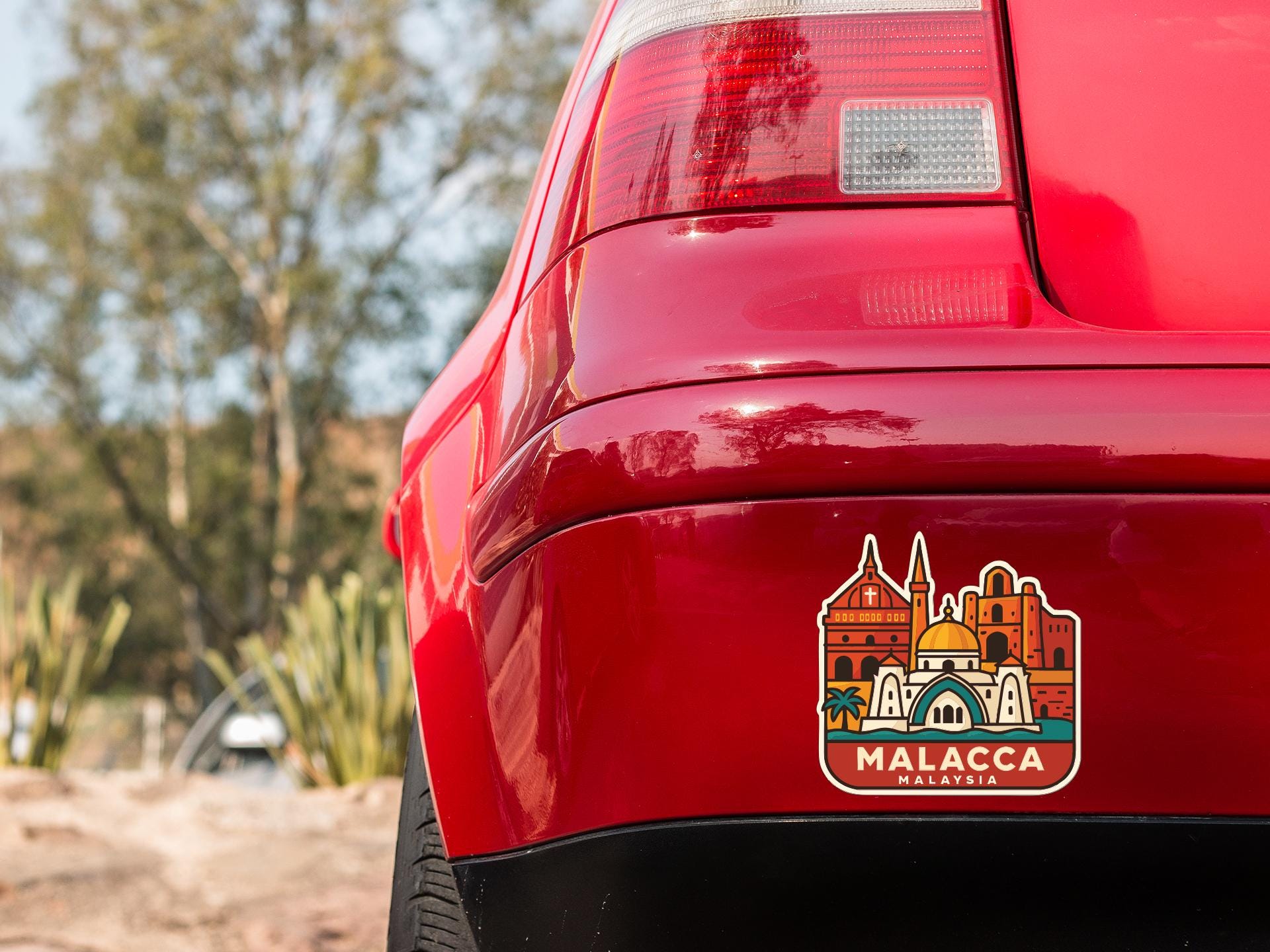 the rear end of a red car with a sticker on the trunk that features a cityscape design.