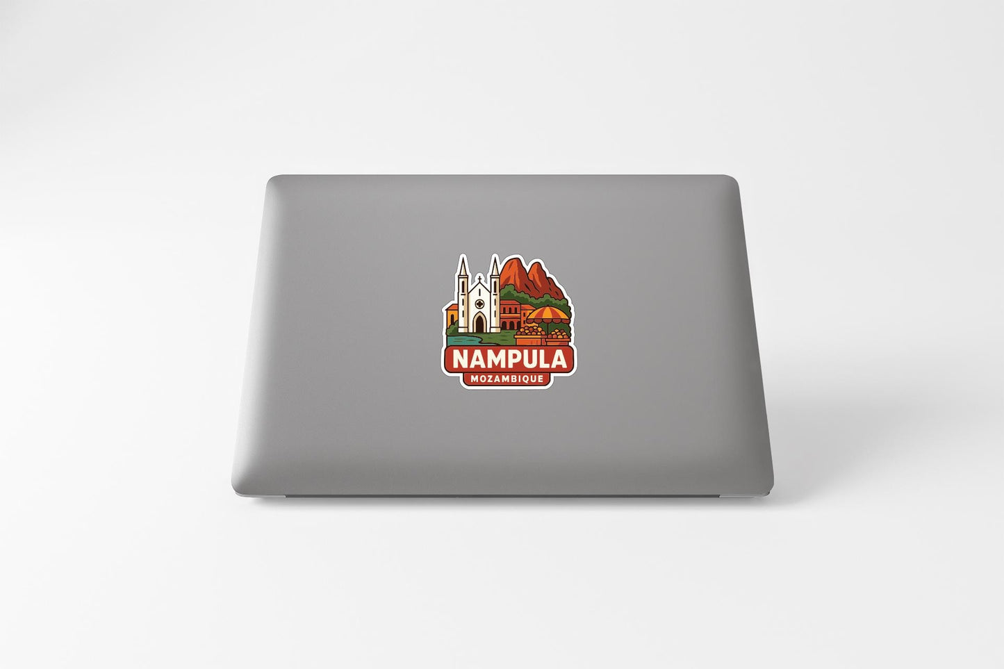 a sticker with a graphic of a building and mountains, along with the text "NAMPULA" and "MAMBIMBOSE" printed on a laptop.