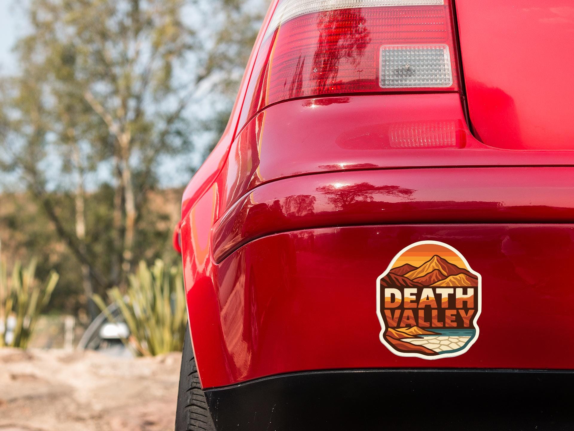 the rear end of a red car with a sticker on the trunk that says "DEATH VALLEY".