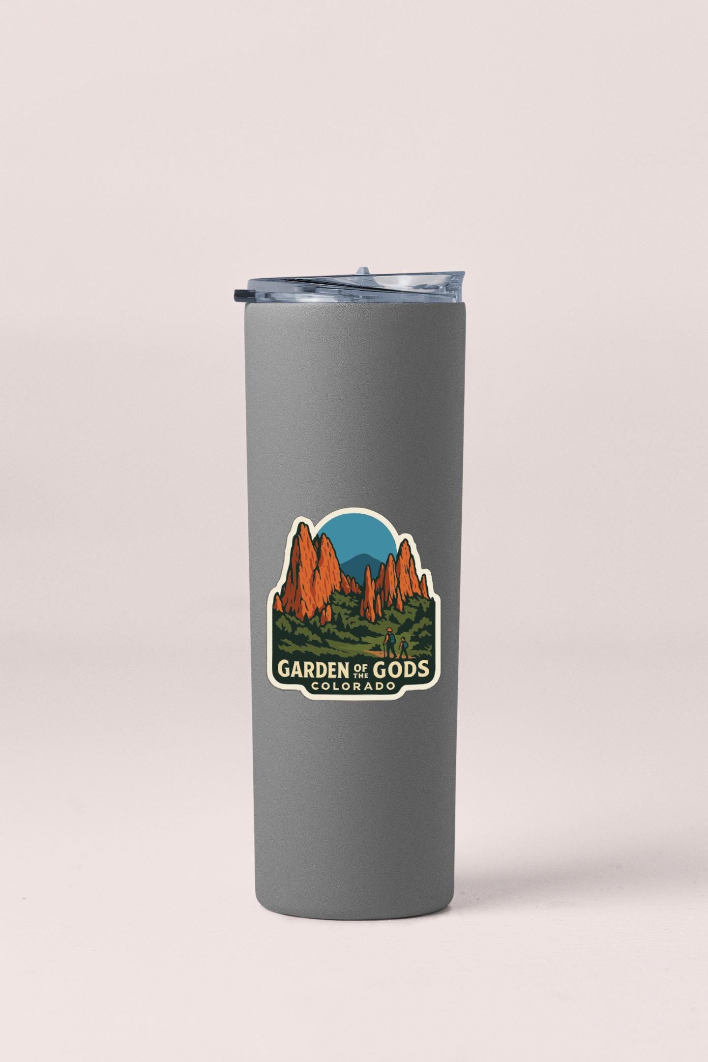 A gray tumbler with a sticker depicting a mountain landscape and the text "Garden of Gods, Colorado".