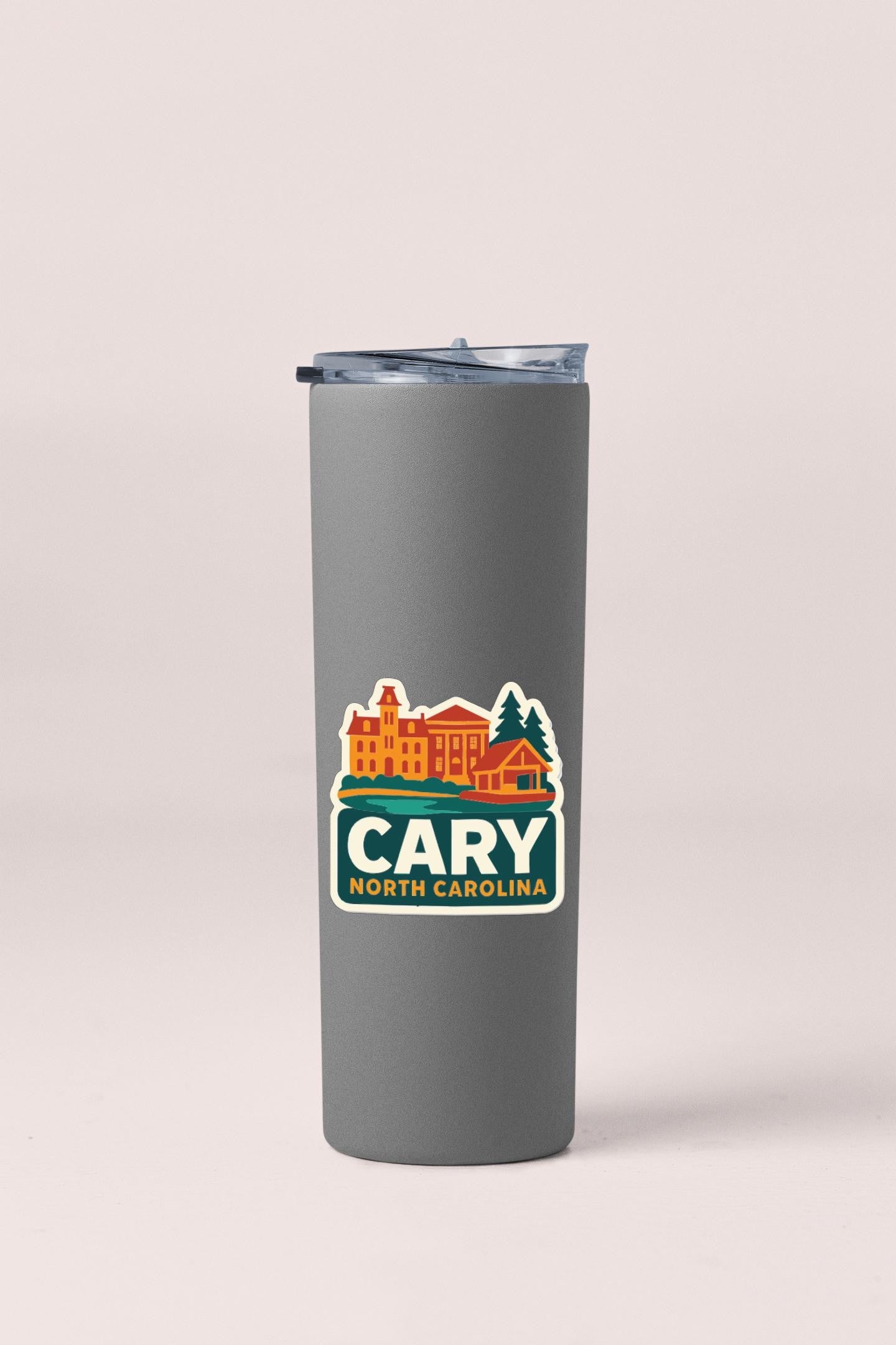 A gray insulated tumbler with a sticker depicting a cityscape and the text "CARY NORTH CAROLINA" printed on it.