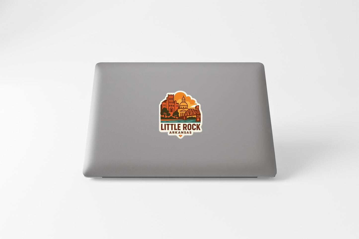a sticker on the back of a laptop with an illustration of a cityscape and the text "LITTLE ROCK ARKANSAS" printed on it.