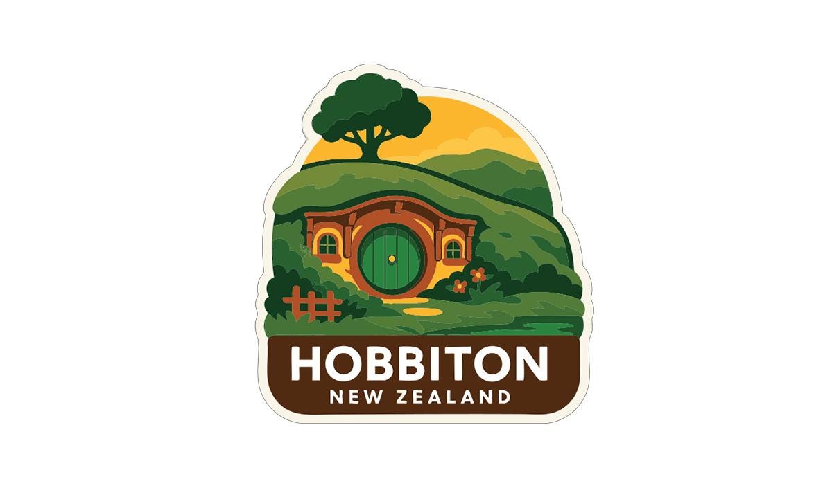 A sticker depicting a house with a green door and a tree, set against a landscape with hills and a sunset, with the text "HOBBITON NEW ZEALAND" below.