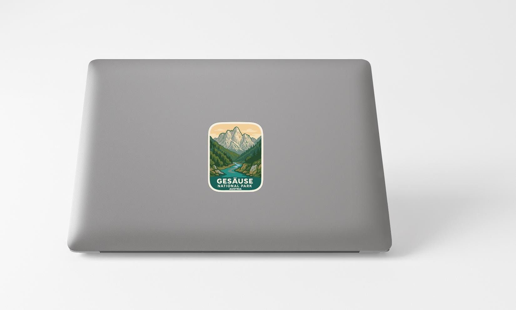 A sticker with a mountain landscape and the text "Gesausse National Park" is placed on the back of a laptop computer.
