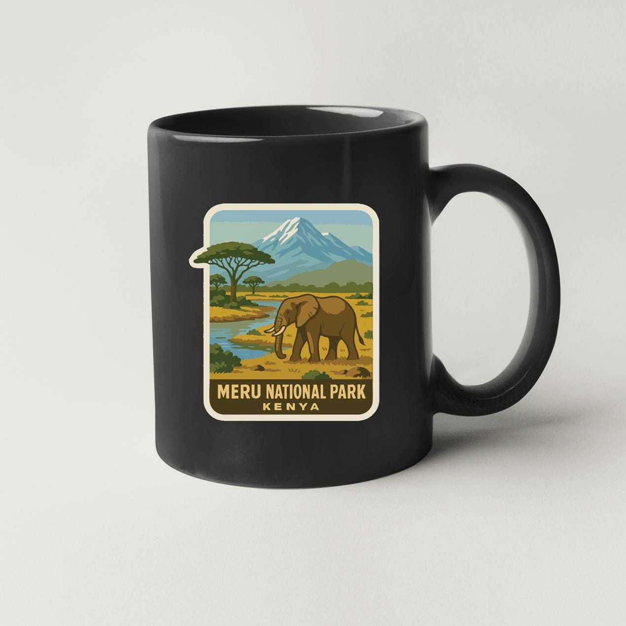 A black coffee mug with a label that features an illustration of an elephant in a savanna landscape with a mountain in the background.