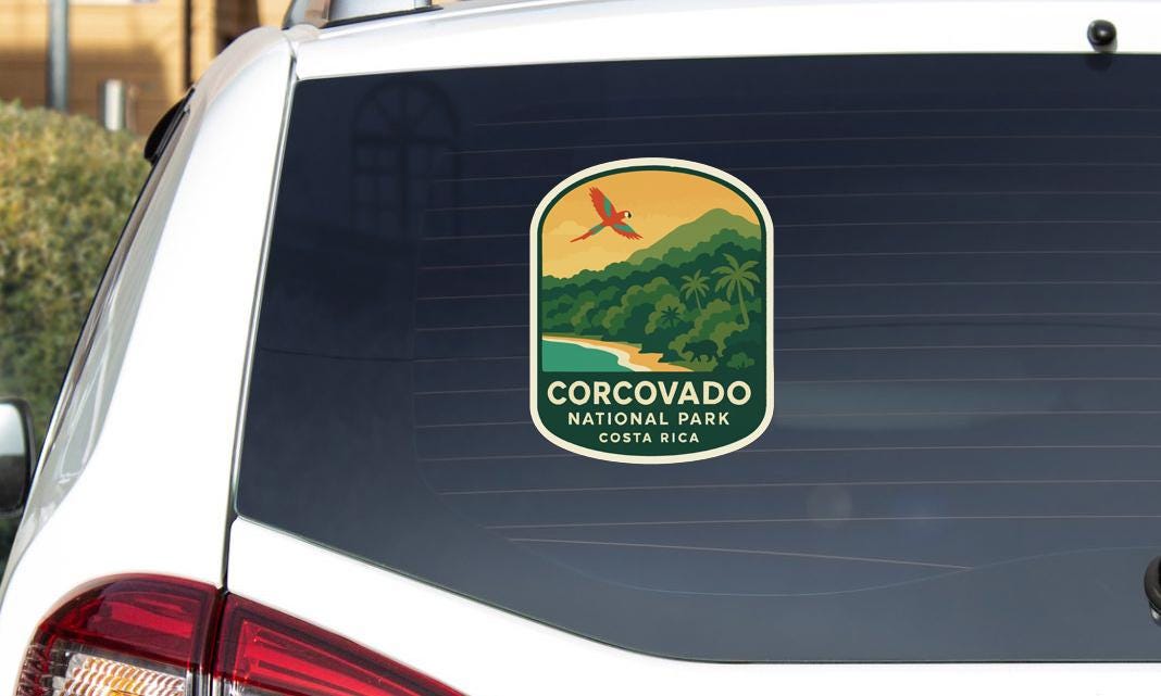 a sticker on the rear window of a vehicle, depicting a tropical landscape with a bird in flight.