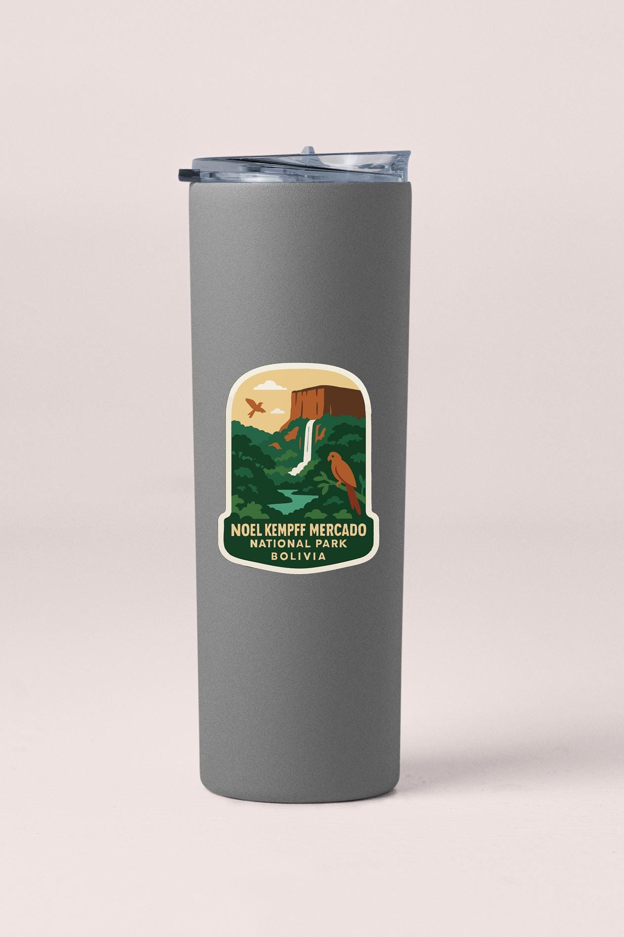 A gray tumbler with a sticker depicting a waterfall and a bird.
