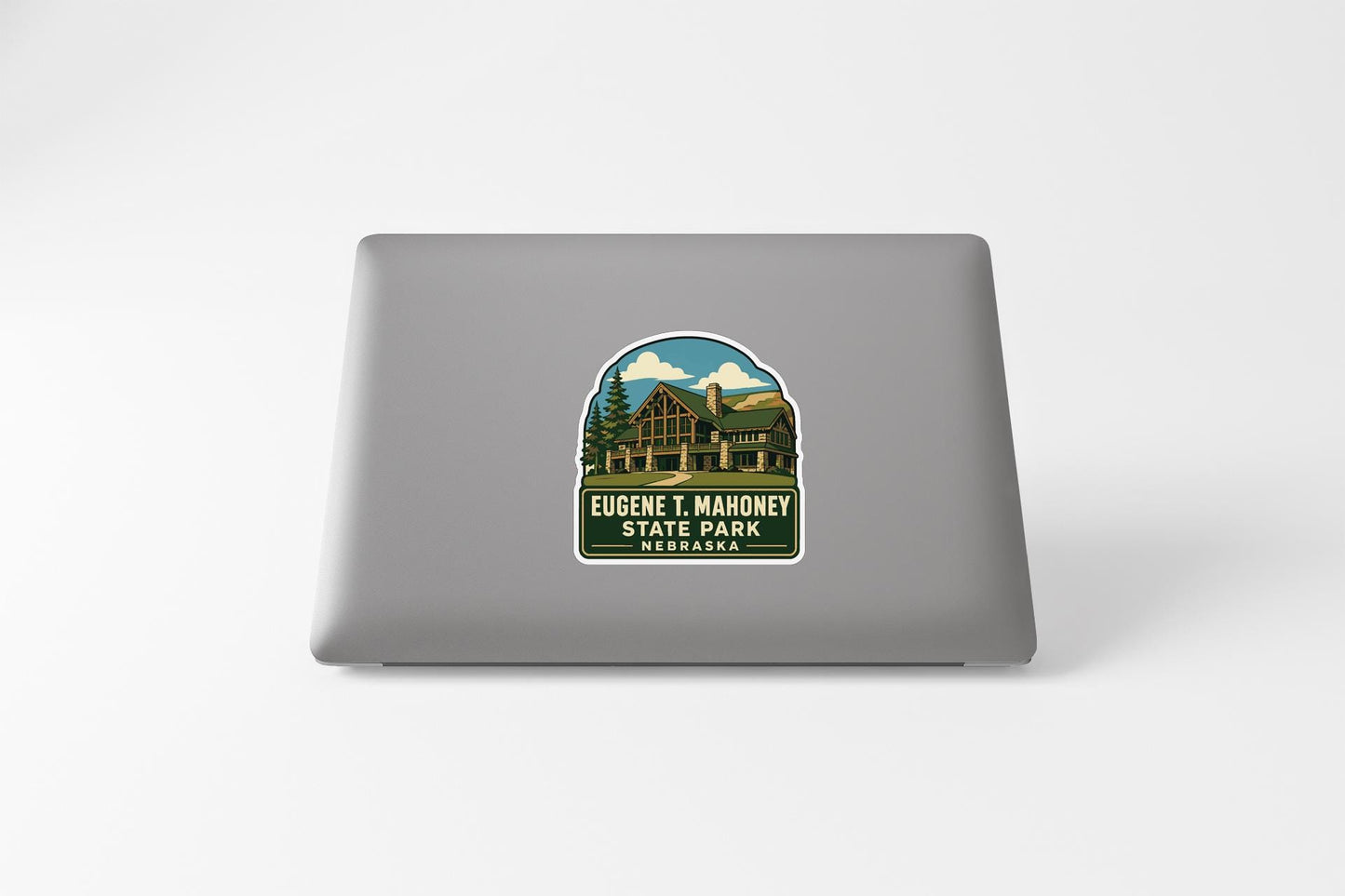A sticker on the back of a laptop, depicting a scenic image of a cabin surrounded by trees and mountains.