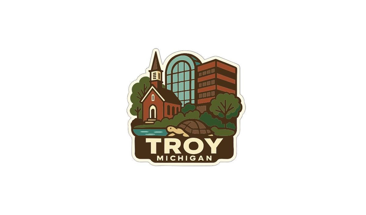 A sticker or emblem featuring a church, a tall building, and a turtle, with the text "Troy, Michigan" prominently displayed.