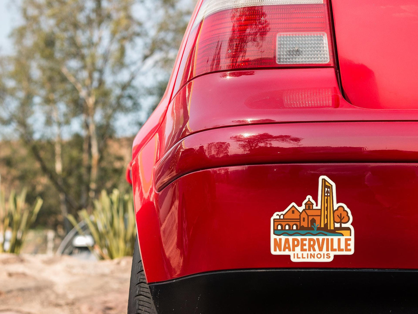the rear end of a red car with a sticker on the trunk that says "Naperville Illinois".