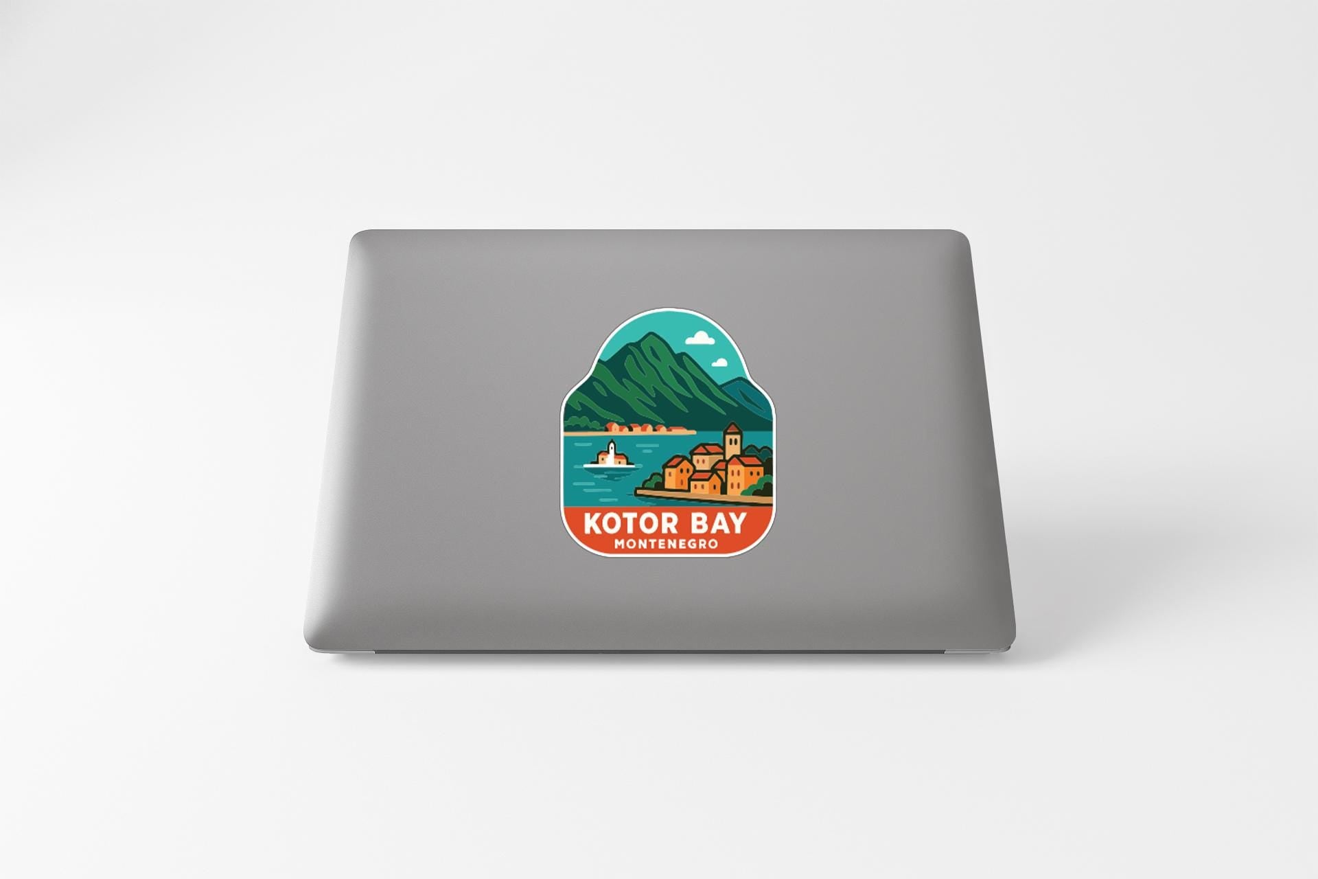 A sticker on the back of a laptop, depicting a scenic view of Kotor Bay, a coastal area in Montenegro.